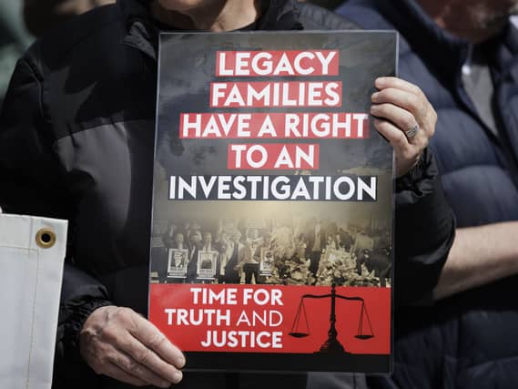 Close-up of a placard being held up that says: Legacy families have a right to an investigation