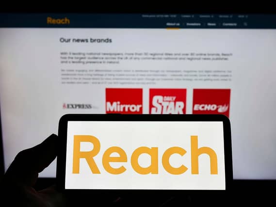 The Reach logo displayed on a smartphone in front of the business webpage