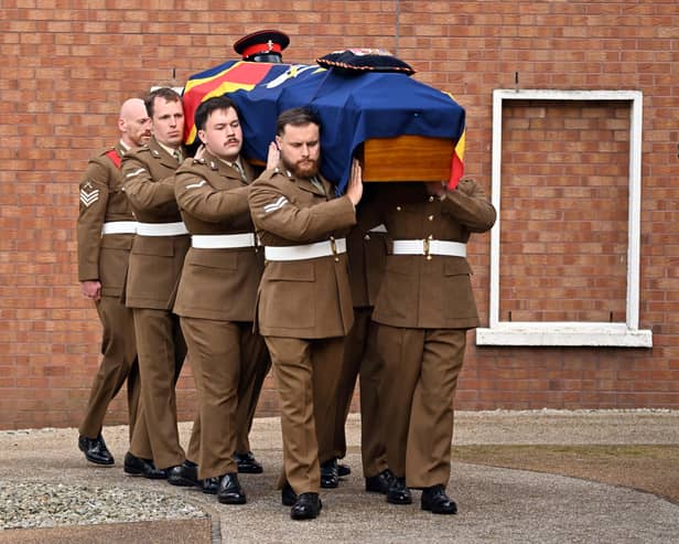 The bearer party carries the coffin into the funeral of Norman Irwin