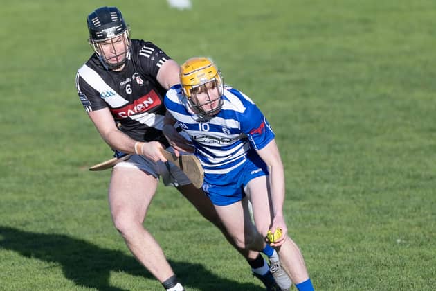 Naas wing-forward Oisin O'Neill holds off the tackling Cathal McCabe of Maynooth before laying off his hand pass