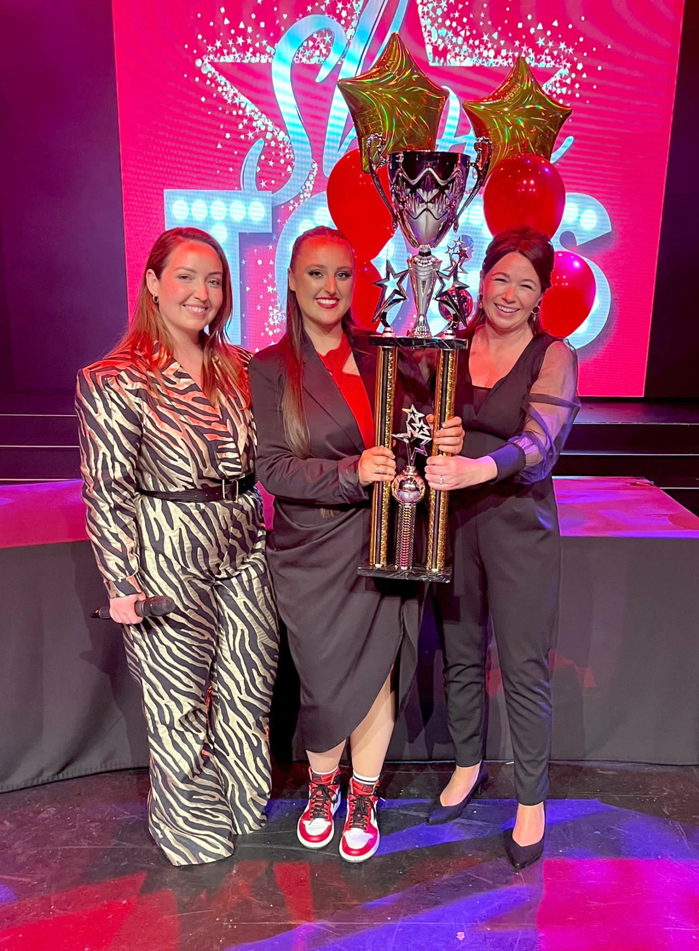 Kim Shortall (Director of ShowTops) and Lisa Price (ShowTops Judge) present Shauna Walsh with the Best overall vocal award trophy